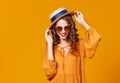 Beautiful young curly woman in summer hat and sunglasses on   yellow background Royalty Free Stock Photo