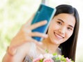 A beautiful young cute black long hair Asian woman holding a sweet color roses bouquet and use smartphone taking a selfie and with Royalty Free Stock Photo