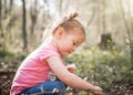 Beautiful young cute girl in woods picking wild flowers in summer sunshine with light rays shining Royalty Free Stock Photo