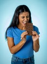Beautiful young cute and happy latin woman in casual clothes holding big delicious chocolate tablet looking with temptation Royalty Free Stock Photo