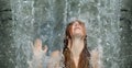 beautiful young cute sexy Portrait of a redhead woman with raised arm under the splashing pattering waterfall burbling water in Royalty Free Stock Photo