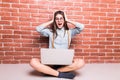 Beautiful young dark-haired girl in casual clothes with laptop, looking in camera and showing surprise Royalty Free Stock Photo