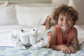 Beautiful young diverse boy sitting on bed in a cruise ship next to a towel animal Royalty Free Stock Photo