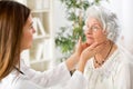 Beautiful young doctor examining senior woman lymph glands