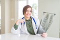 Beautiful young doctor woman looking at chest radiography with surprise face pointing finger to himself