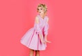 Beautiful young doll face woman model with fashion makeup in glamour pink dress posing on pink background. Marilyn Royalty Free Stock Photo