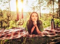 Beautiful young dreaming girl lying on a plaid in a forest glade during sunset bright sunlight around beauty of nature Royalty Free Stock Photo