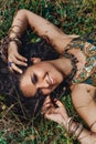 beautiful young eastern girl in ethnical jewelry lying on a grass on a field