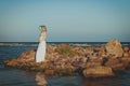 Beautiful young elegant pregnant blond woman in a blue hat walks on the beach, seashore at sunset. sea. Motherhood. Royalty Free Stock Photo