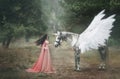 Beautiful, young elf, walking with a unicorn in the forest She is dressed in a long orange dress with a cloak. The plume beautiful