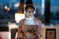 Beautiful young entrepreneur woman using her digital tablet while listening music standing in the office Royalty Free Stock Photo