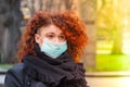 Beautiful young European woman in spring clothes on the street with a medical face mask on. Royalty Free Stock Photo