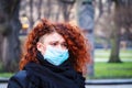 Beautiful young European woman in spring clothes on the street with a medical face mask on Royalty Free Stock Photo