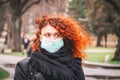 Beautiful young European woman in spring clothes on the street with a medical face mask on Royalty Free Stock Photo