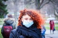 Beautiful young European woman in spring clothes on the street with a medical face mask on Royalty Free Stock Photo