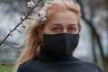 Beautiful young European woman in spring clothes on the street with a medical face mask on. coronavirus - Covid19 Royalty Free Stock Photo