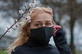 Beautiful young European woman in spring clothes on the street with a medical face mask on. coronavirus - Covid19 Royalty Free Stock Photo