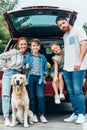 beautiful young family with dog standing next to car Royalty Free Stock Photo