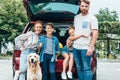 beautiful young family with dog standing next to car ready Royalty Free Stock Photo