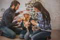 Beautiful young family enjoying their holiday time together, decorating Christmas tree, arranging the christmas lights Royalty Free Stock Photo