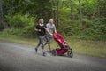 Couple exercising and jogging together pushing their baby in a stroller Royalty Free Stock Photo