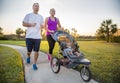 Couple exercising and jogging together at the park pushing their baby in a stroller Royalty Free Stock Photo