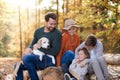 Beautiful young family with small children and dog sitting autumn forest. Royalty Free Stock Photo