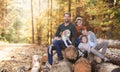 Beautiful young family with small children and dog sitting in autumn forest. Royalty Free Stock Photo