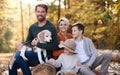 Beautiful young family with small children on a walk in autumn forest.