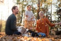 Beautiful young family with small daughter and dog sitting in autumn forest. Royalty Free Stock Photo