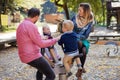 Beautiful young family with small twins playing on playground in autumn. Royalty Free Stock Photo
