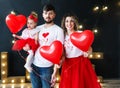 Beautiful young family and their little daughter pose with balloons in a cosy studio. Royalty Free Stock Photo