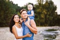 Beautiful young family on vacation with baby. The father holds the blonde girl in her arms, and the brunette`s mother hugs her hu Royalty Free Stock Photo