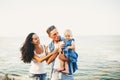 Beautiful young family on vacation with baby. The father holds the blonde girl in her arms, and the brunette`s mother hugs her hu