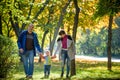 Beautiful young family on a walk in autumn forest on maple yellow trees background. Father and mother hold son on hands. Happy fa Royalty Free Stock Photo