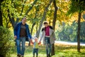 Beautiful young family on a walk in autumn forest on maple yellow trees background. Father and mother hold son on hands. Happy Royalty Free Stock Photo