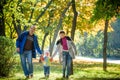 Beautiful young family on a walk in autumn forest on maple yellow trees background. Father and mother hold son on hands. Happy Royalty Free Stock Photo