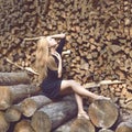 Beautiful young fashion woman posing on firewood wood