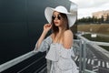 Beautiful young fashionable girl in a stylish summer hat with vintage round black sun glasses in a trendy striped top looks at the Royalty Free Stock Photo