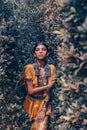 Beautiful young fashionable woman with make up and stylish boho accessories posing on natural tropical background