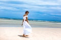 Beautiful young fashionable woman in white dress walking by the