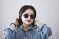 Beautiful young fashionista girl in trendy jeans jacket and sunglasses. Portrait of attractive and cute female smiling to the