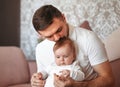 Beautiful young father kisses newborn daughter in a light room