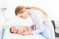 Beautiful young female blonde pediatrician doctor examines baby girl checking her skin Royalty Free Stock Photo