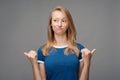 Beautiful young female with blonde straight hair looking away holding two thumbs down. Concept of dislike Royalty Free Stock Photo