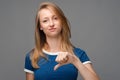 Beautiful young female with blonde straight hair looking is upset at the camera, holding thumb down. Concept of dislike Royalty Free Stock Photo