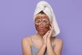 Beautiful young female with chocolate mask on face, poses with white towel on head, having spa procedures at home, isolated over Royalty Free Stock Photo
