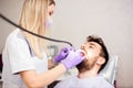 Beautiful young female dentist polishing teeth of a young male patient in dental clinic Royalty Free Stock Photo