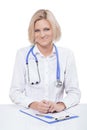 Beautiful young female doctor sitting near the table looking at Royalty Free Stock Photo