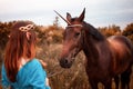 Beautiful young female elf with long dark wavy hair petting her horse resting in the woods forest nymph stroking her horse care Royalty Free Stock Photo